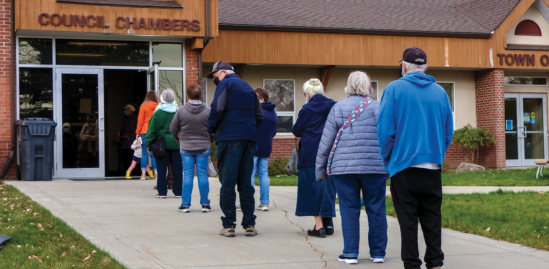 People stand in line outside Pincher Creek council chambers waiting to vote