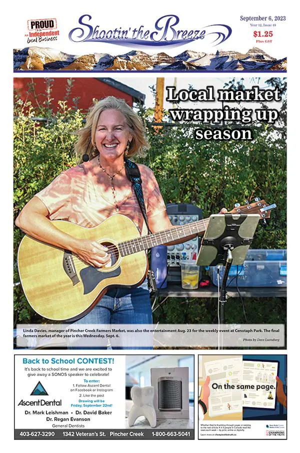 Blonde woman smiling and singing while playing guitar on the front page of Shootin' the Breeze Newspaper