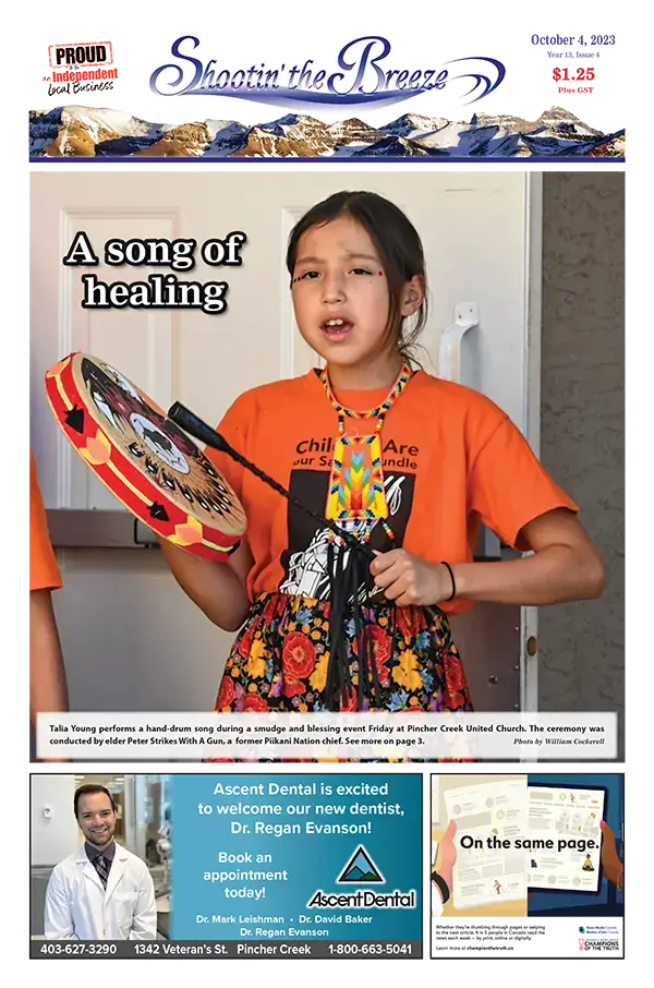 Talia Young, an Indigenous girl wearing an orange "every child matters" shirt sings and drums.