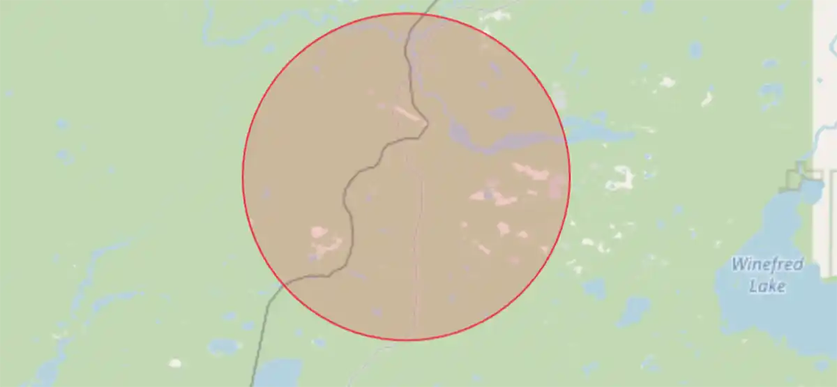 A map shows a large brownish area within a red circle, intersected by a winding black line, with green and blue areas outside the circle. Winefred Lake is labeled to the right.