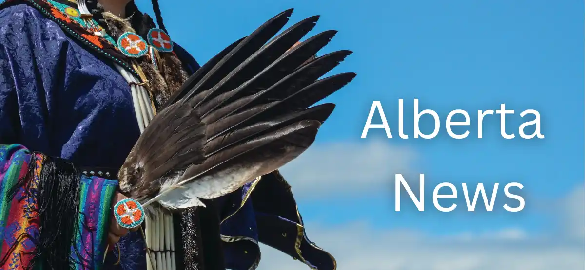 A person in traditional Indigenous clothing holds a fan made of feathers against a blue sky. Text reads "Alberta News.