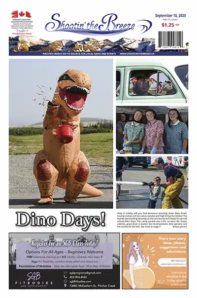 Person in inflatable T-Rex costume tosses candy during Cowley Dino Days parade on Main Street
