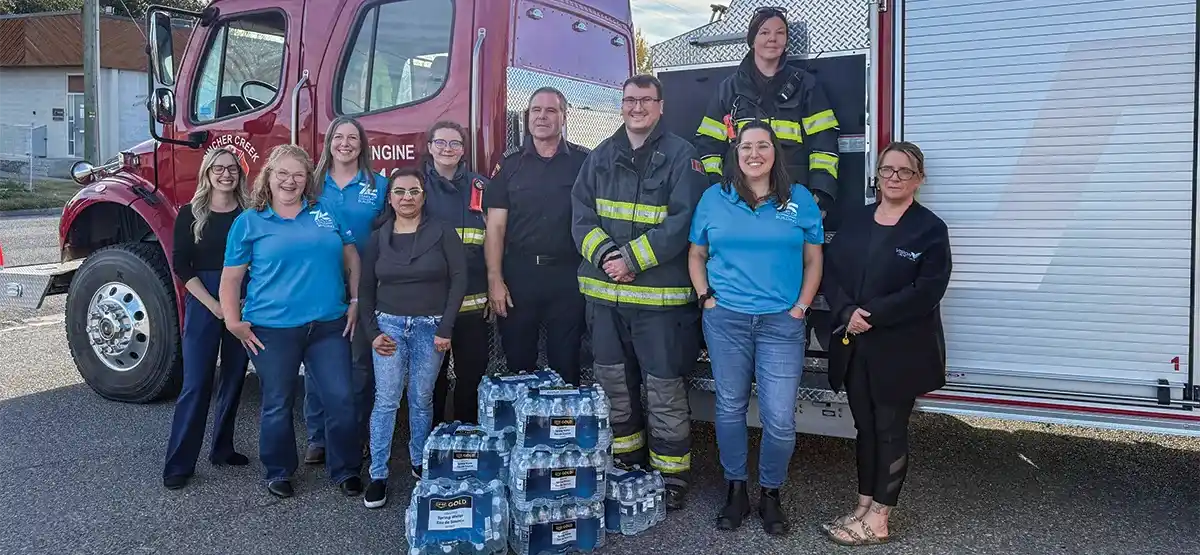 Group of Vision Credit Union staff and emergency services members standing with cases of water bottles