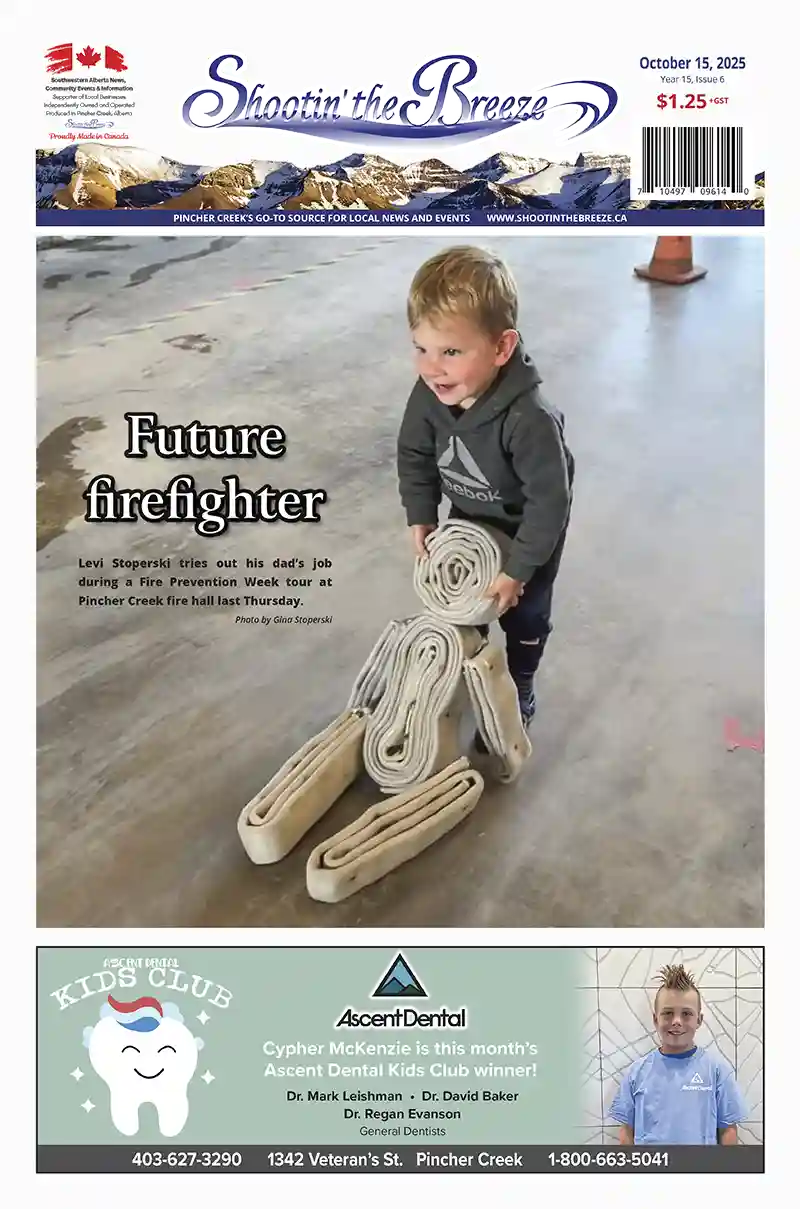 Young boy carrying fire hoses during Fire Prevention Week tour at Pincher Creek fire hall